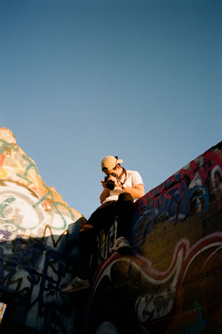 man taking photo using camera while sitting on top of graffiti wall, HD wallpaper