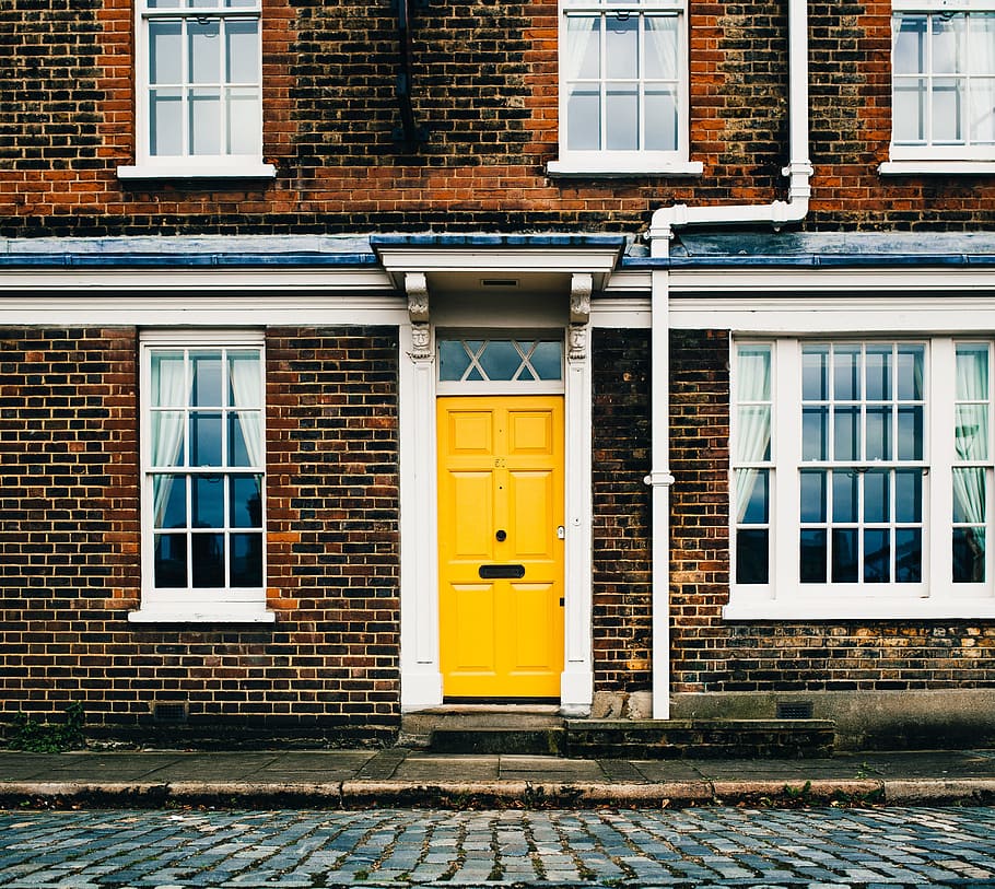 Yellow entrance door on a brick home with white windows, architecture