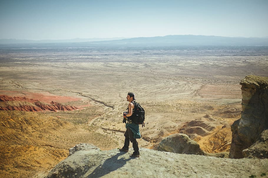 Man Standing on Peak, adventure, arid, backpack, camera, cap HD wallpaper