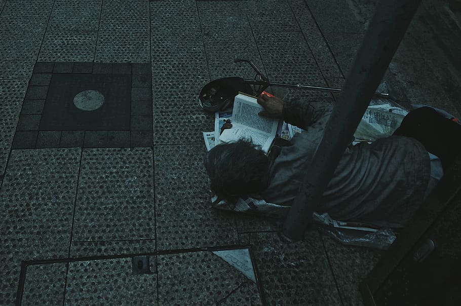 man lying on grey paper while reading bible, high angle view HD wallpaper