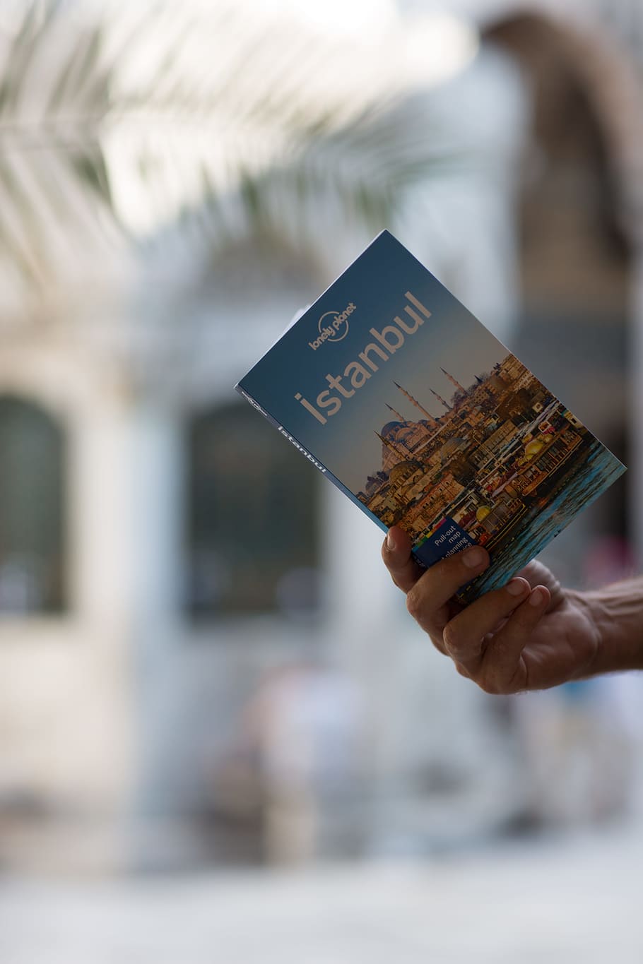 person holding Istanbul book, guidebook, hand, light, journey HD wallpaper