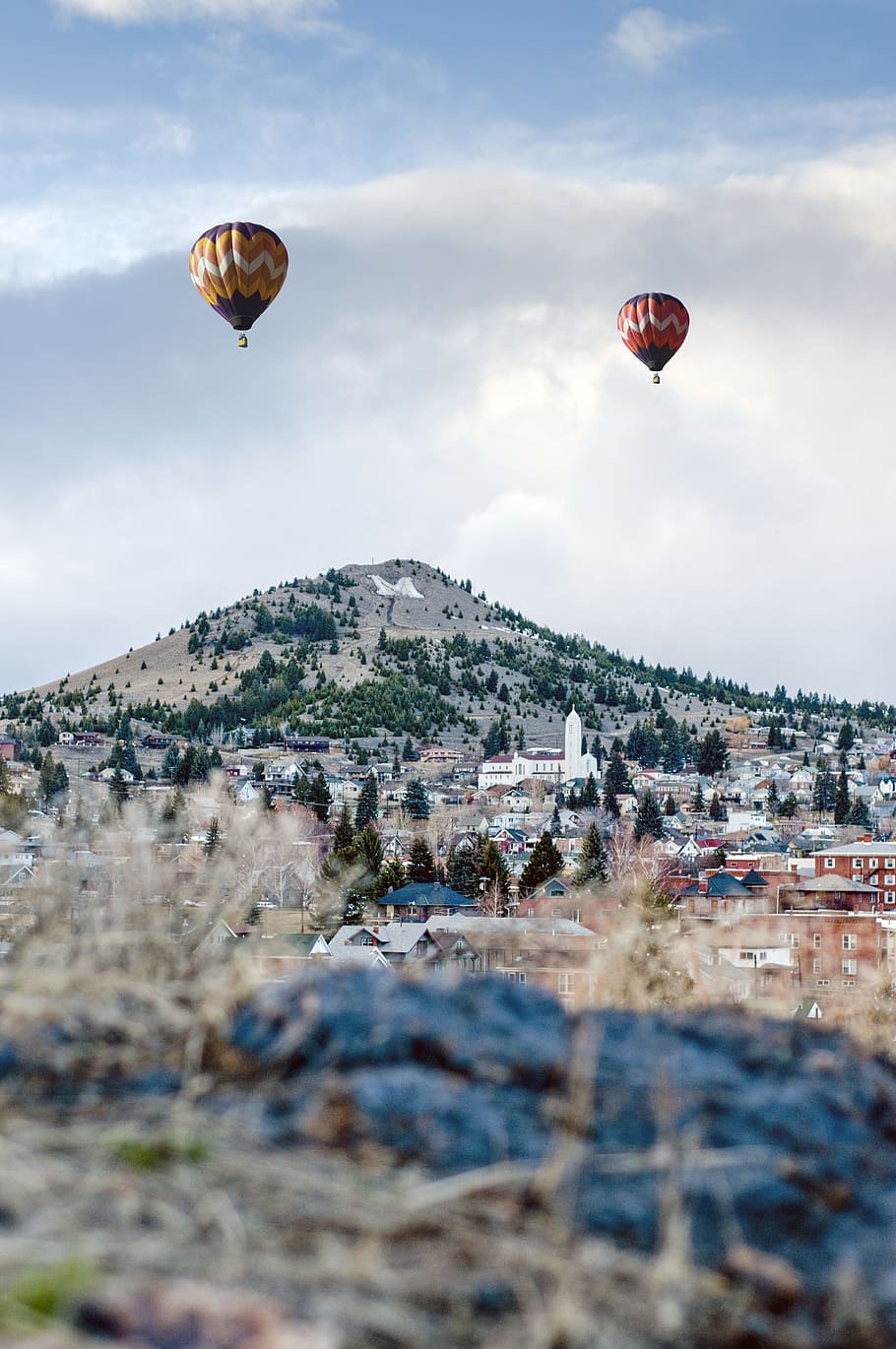 two assorted-color hot air balloons on air near mountain at daytime HD wallpaper