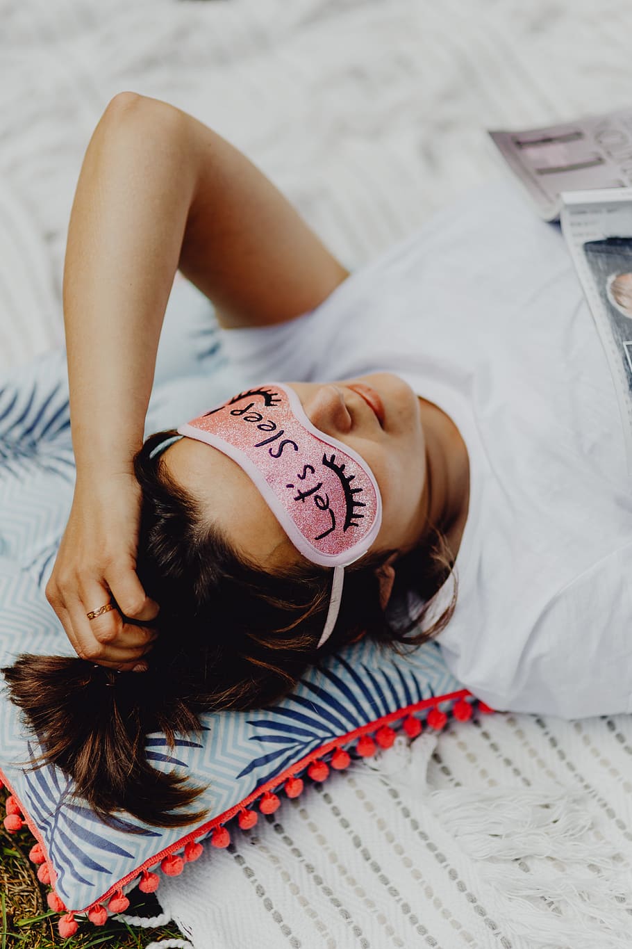 Joyful girl relaxing in bedroom - top view of brunette women in pink sleeping mask