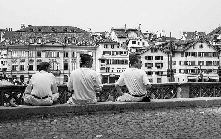 Grayscale Photography of Three Mans Sitting Near High-rise Building HD wallpaper