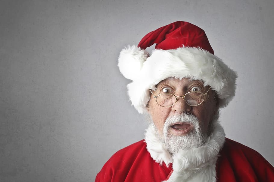 Old Aged Man wearing a Santa Claus costume and making surprised face on Isolated On Grey Background