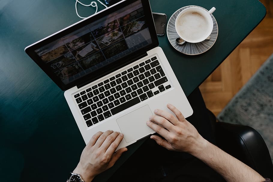 Male working with a laptop and a cup of coffee, desk, office