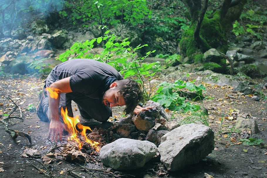 Man Checking Bonfire at Forest, adventure, camping, daylight HD wallpaper