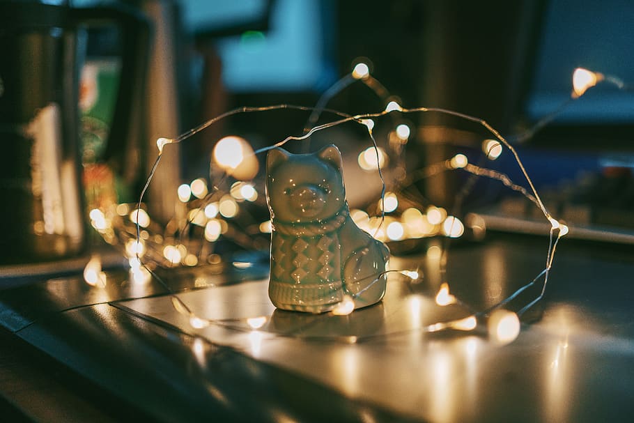 Close-up Photo of Gray Ceramic Cat Figurine Near String Lights HD wallpaper