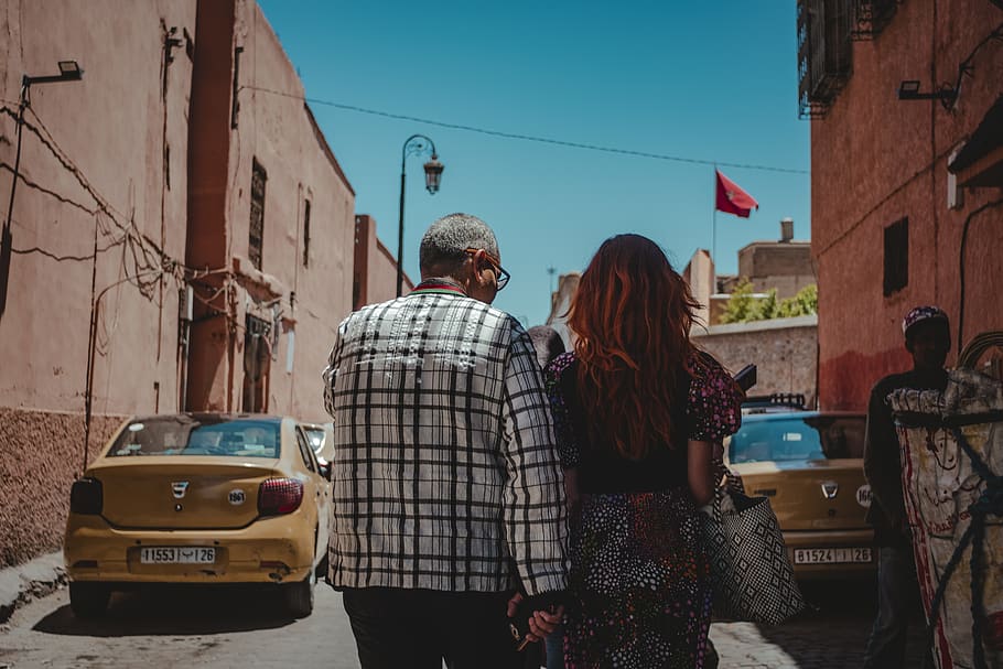 man and woman facing backward while walking on alley, human, person