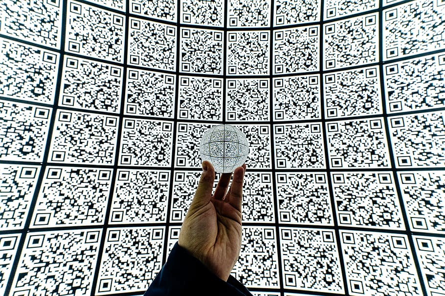 person holding clear glass ball with QR code background, one person
