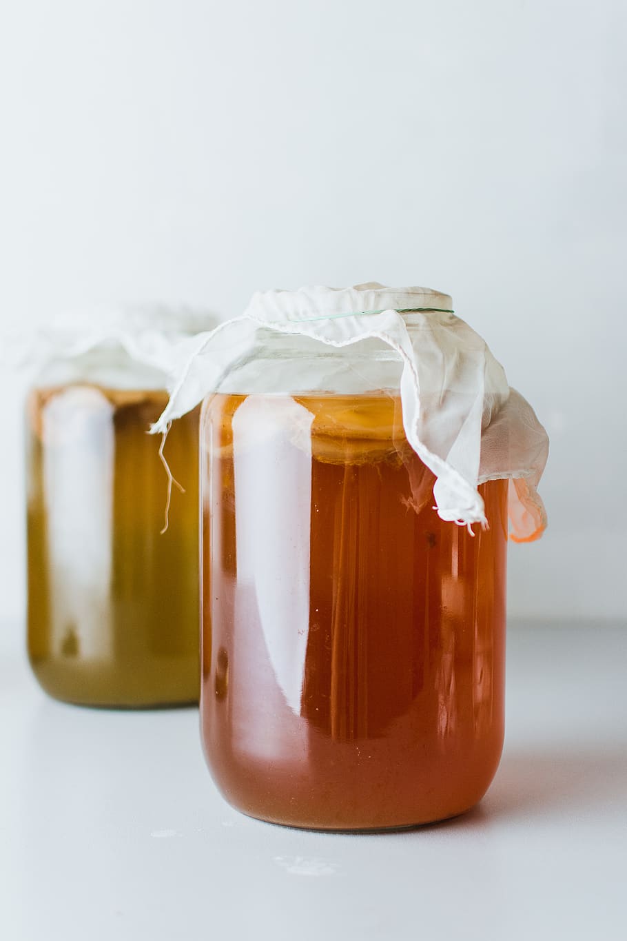 two mason jars filled with liquid on white surface, food, honey