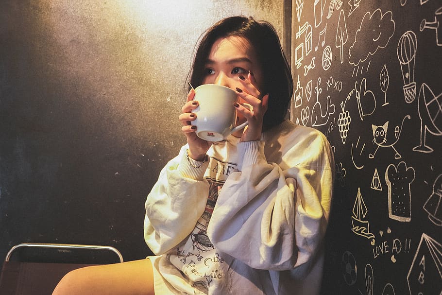 Woman Wearing White over Shirt Holding White Ceramic Mug Beside Black Printed Wall HD wallpaper