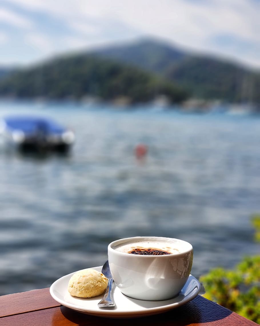 Close-up Photo of White Ceramic Teacup on Saucer Beside Body of Water HD wallpaper