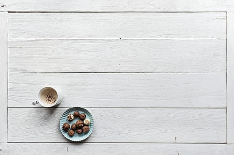White Mug Filled With Coffee Beside Baked Pastries on Paper Plate All on Top of White Wood Surface HD wallpaper