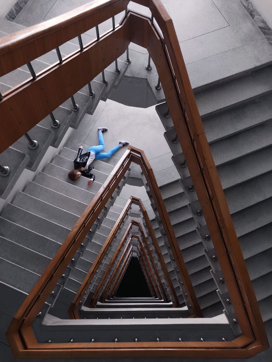 Person In Black Jacket And Blue Denim Pants Laying On Spiral Staircase HD wallpaper
