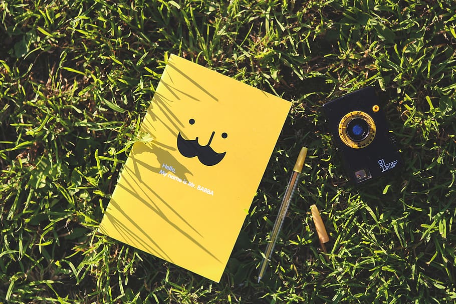 Yellow notebook on the grass, camera, color, design, environment HD wallpaper