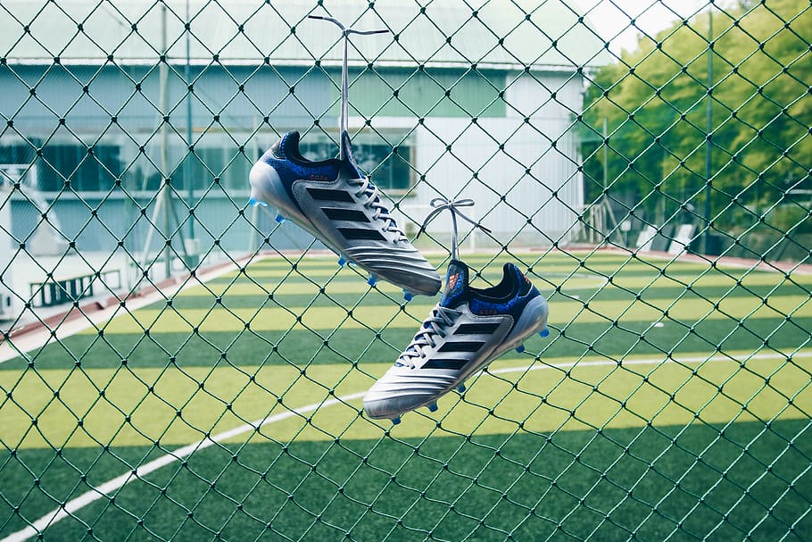 pair of soccer cleats on cyclone fence, shoe, footwear, running shoe, HD wallpaper