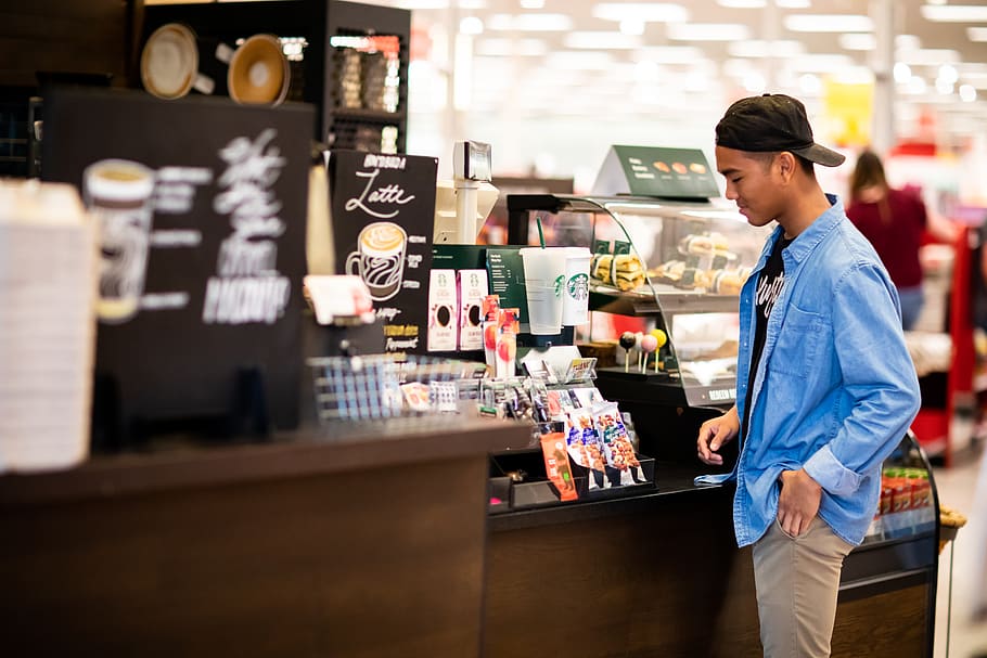 man standing in front cashier, person, human, shop, clothing