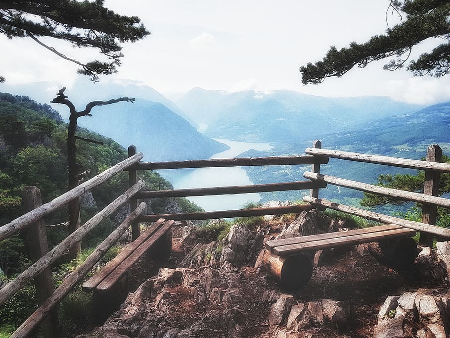 brown wooden bench on top of mountain near river, handrail, banister