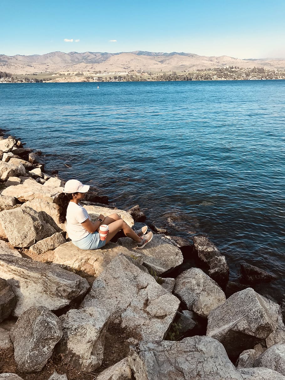 Woman Sitting on Rock Near Body of Water, bay, calmness, cap HD wallpaper
