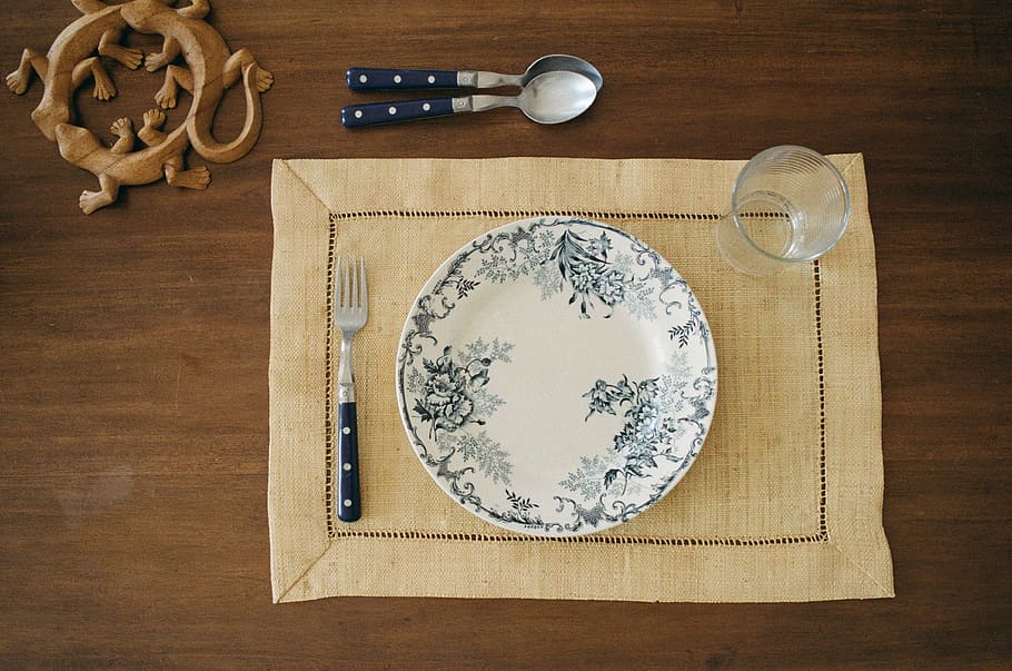 round white and gray plate and fork on brown placemat, cutlery