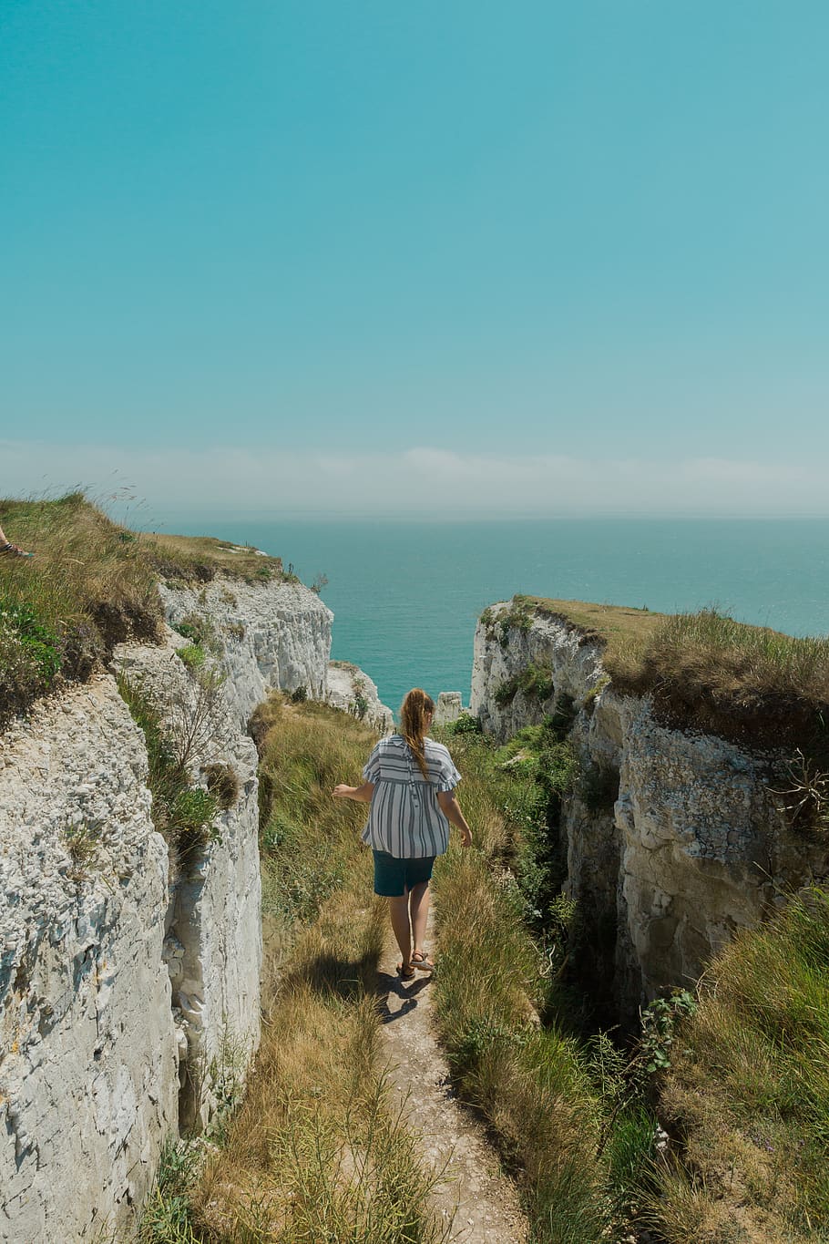 Woman Walking On Pathway Between Rocks, cliff, daylight, ocean HD wallpaper