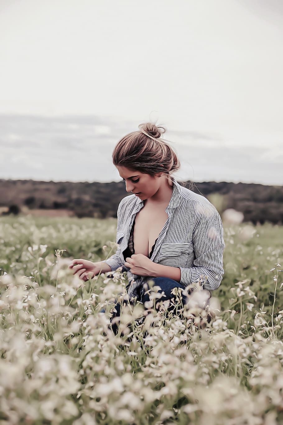 Photo of Woman With Opened Cleavage Knelling in the Middle of Grass Field