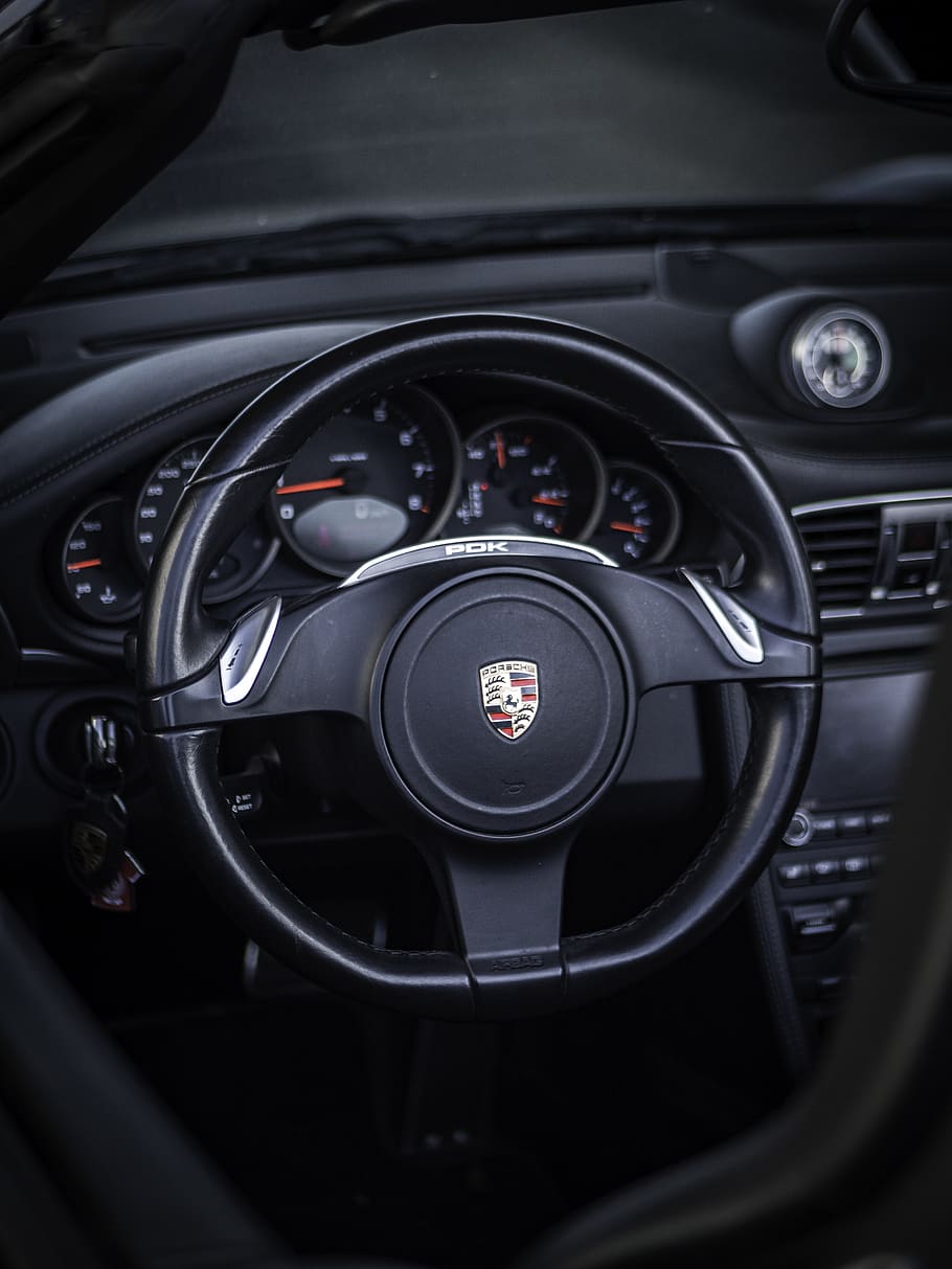 selective focus photography of Porsche vehicle steering wheel