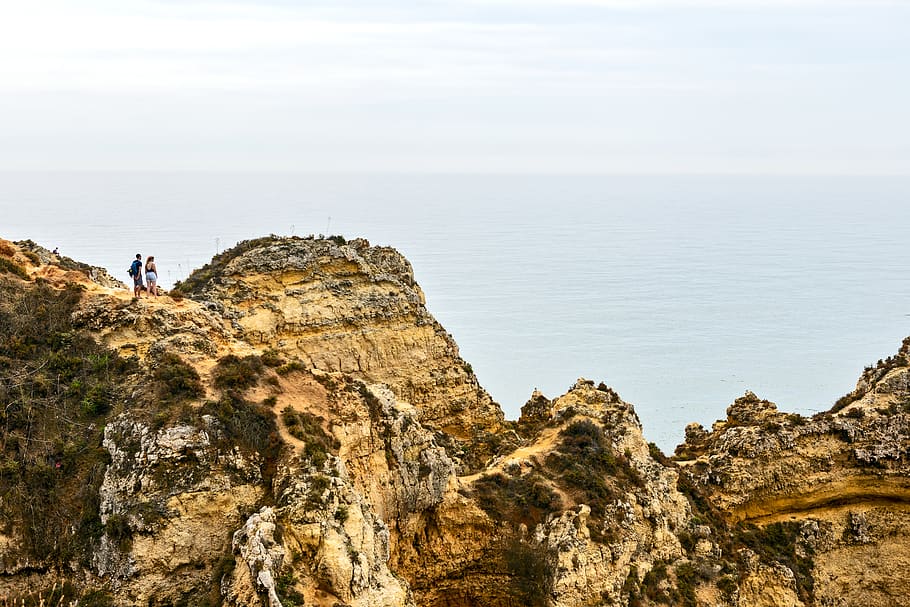 Person Standing on Mountain Overlooking Body of Water, cliff HD wallpaper