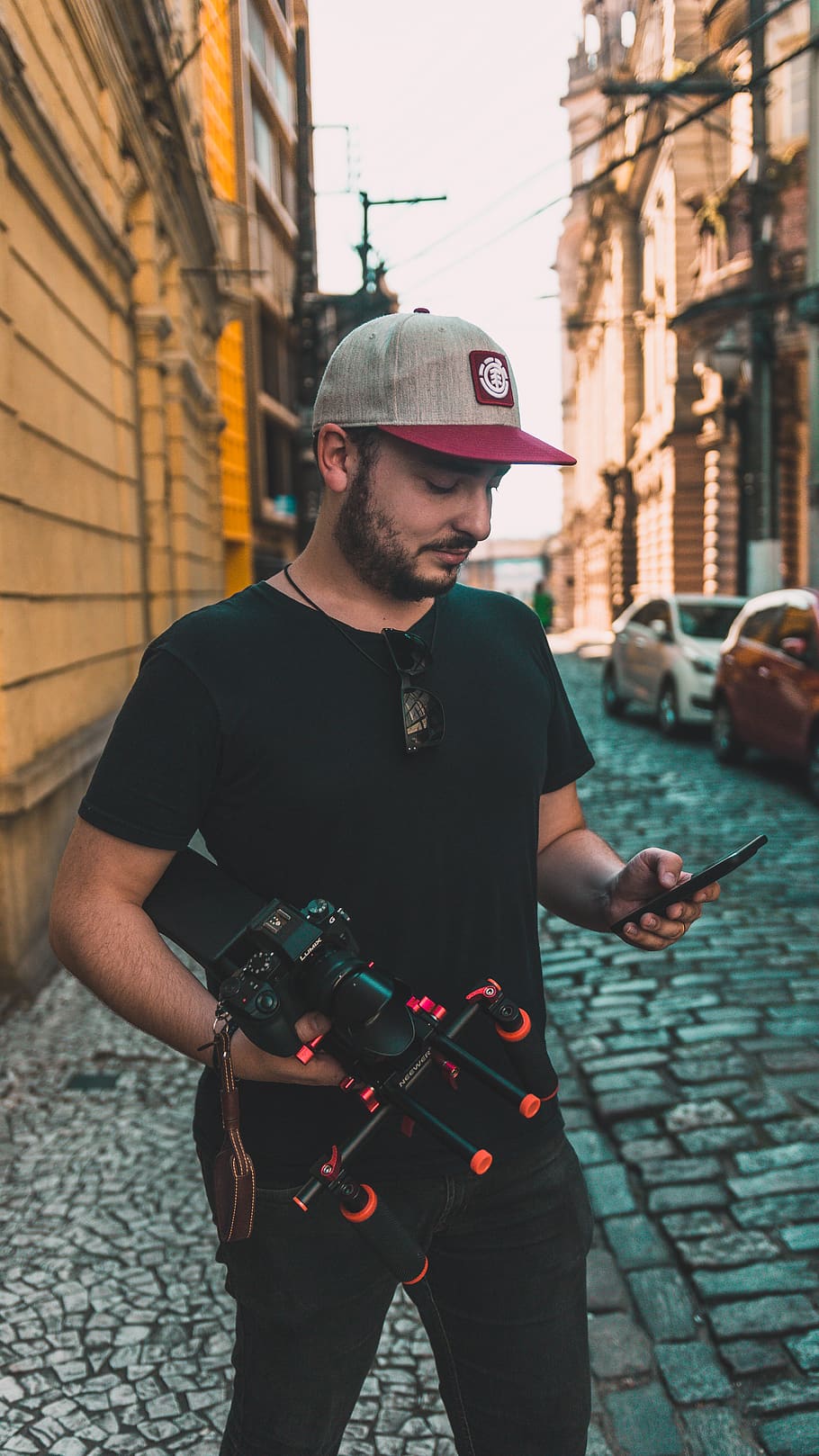 Man Looking at Smartphone at Street, camera, cap, film maker HD wallpaper