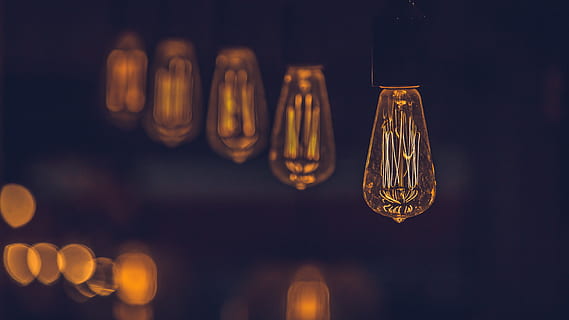 Close up of an Edison-style light bulb with several other such bulbs in the blurred background HD wallpaper