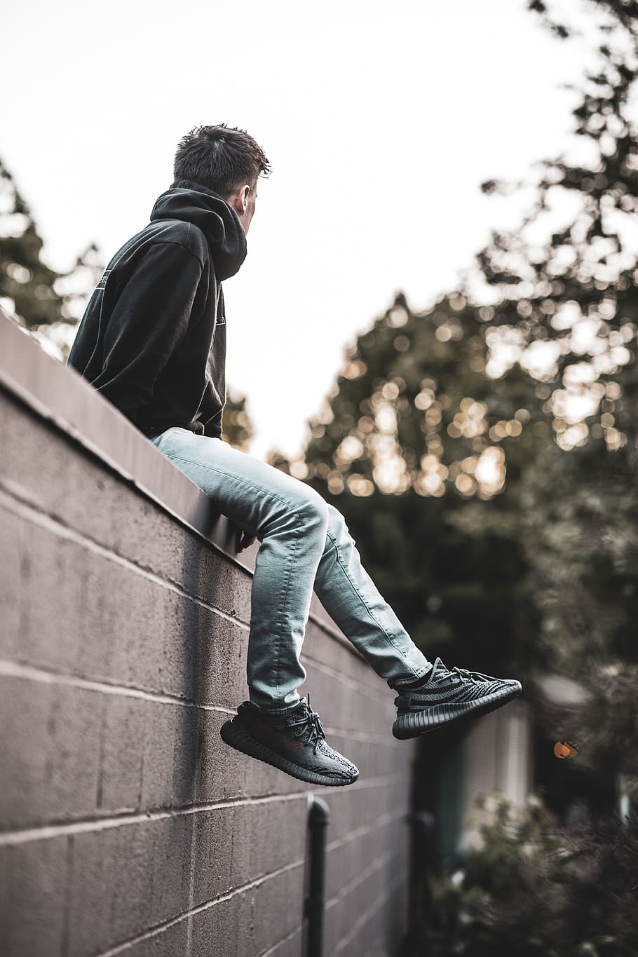 man sitting top of wall during daytime, apparel, clothing, human
