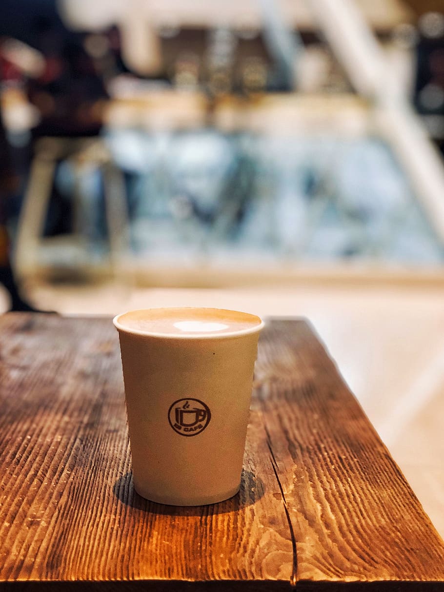 filled white disposable cup on table, wood - material, focus on foreground HD wallpaper