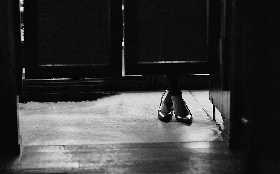 grayscale photography of person in heeled shoes beside door, foot