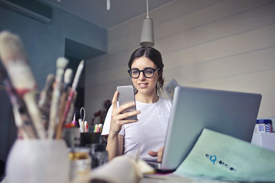Woman in White T-shirt Holding Smartphone in Front of Laptop HD wallpaper
