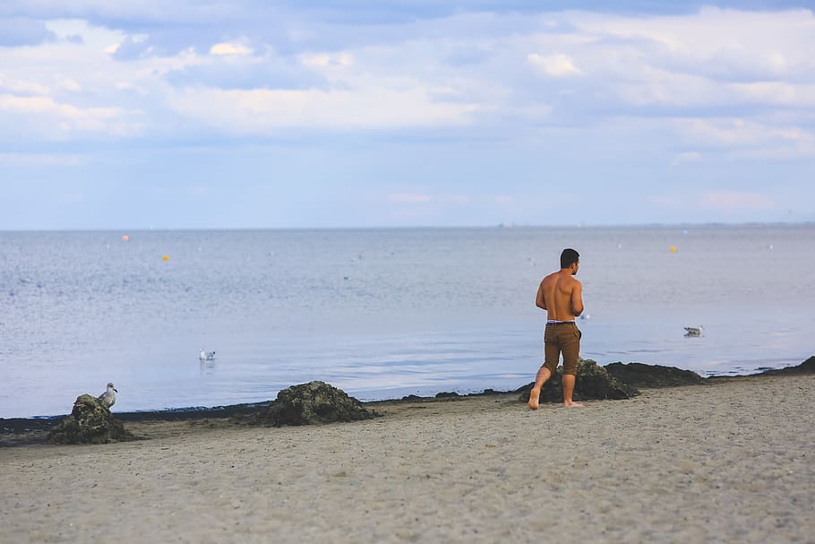 Young man walking on sand beach, boy, clouds, daylight, guy, handsome HD wallpaper
