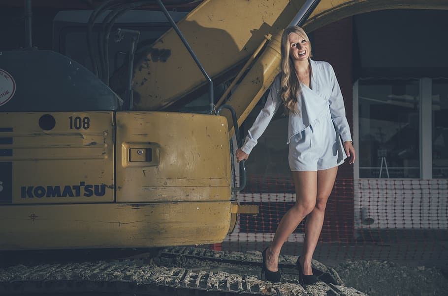 Photo of Laughing Woman In Blue Romper Holding While Standing on Excavator, HD wallpaper