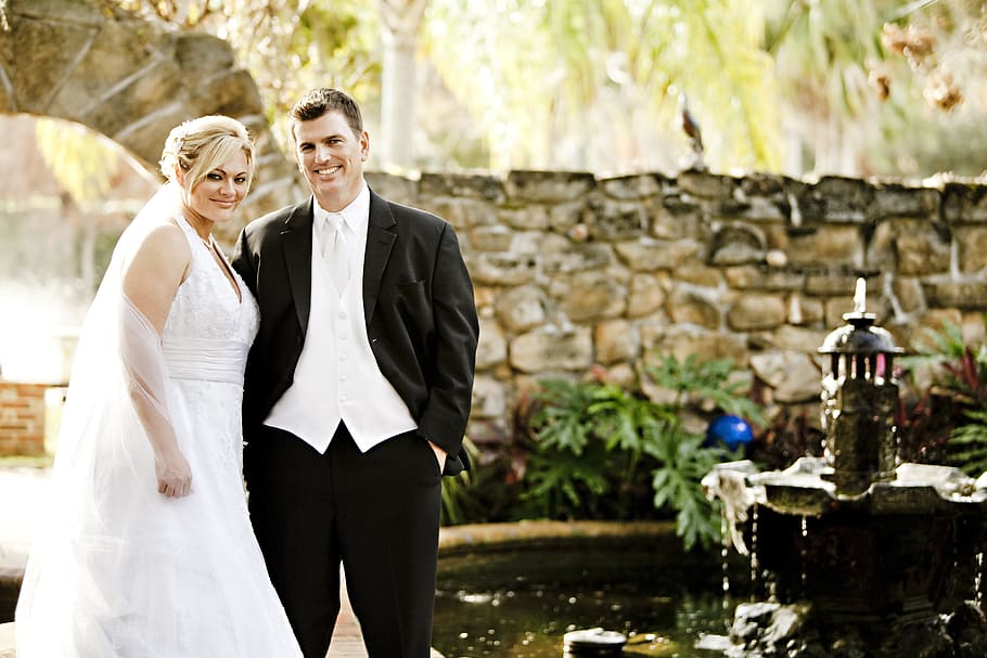 Man and Woman in Their Wedding Outfit With Brown Wall in the Background Near Fountain and Pond during Daytime, HD wallpaper