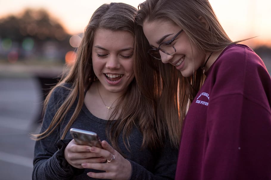 selective focus photo of two women looking on black smartphone
