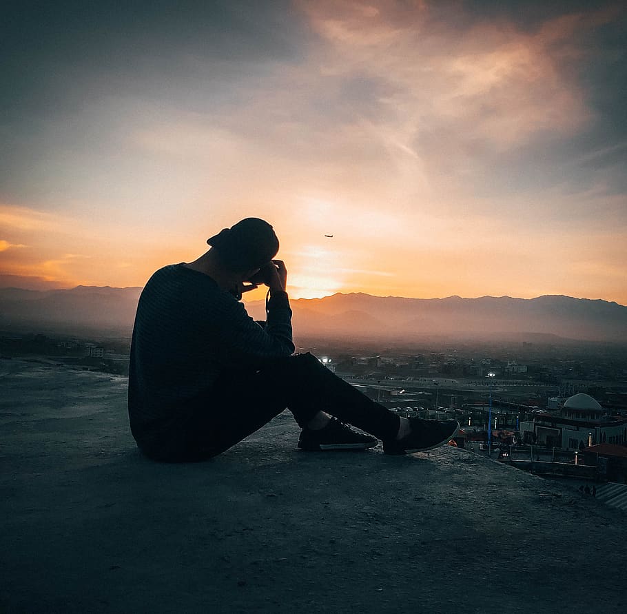 Man Sitting On Concrete Ground, backlit, dawn, dusk, person, silhouette HD wallpaper