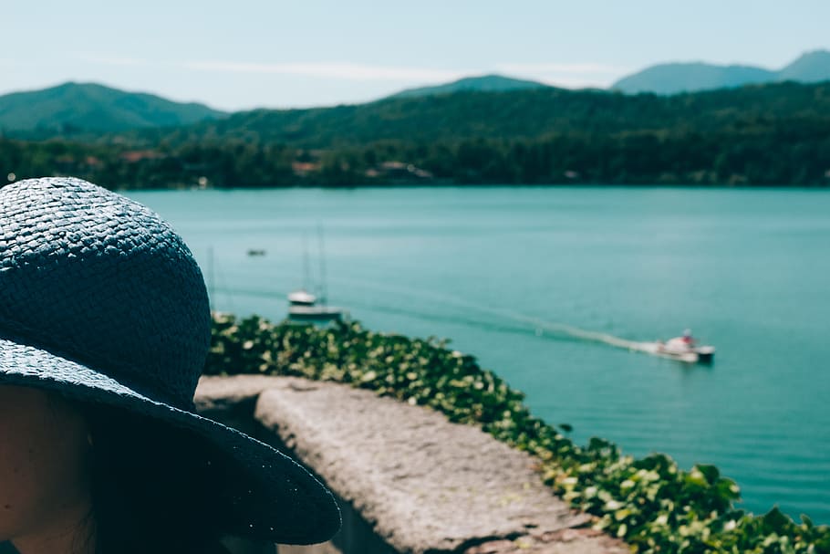 Girl in blue hat in front of mountain lake in Italy, activity