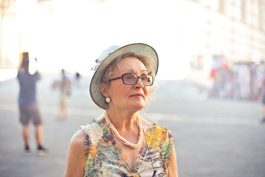 Close-up Of Old Aged Woman In Pastel Color Top, Sunhat And Spectacles Walking on the street, HD wallpaper