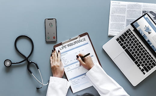 Person Holding Pen and Life Insurance Paper Beside Macbook Pro HD wallpaper