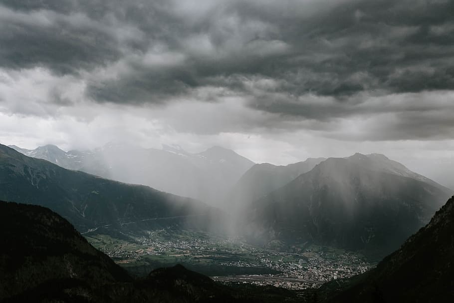 aerial photography of cities surrounded of mountain during gray clouds HD wallpaper