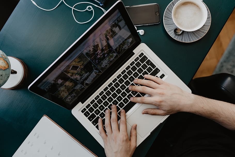 Male working with a laptop and a cup of coffee, desk, office