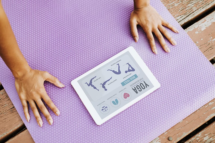 Person Doing Yoga While Looking at Silver Ipad, acro yoga, close-up