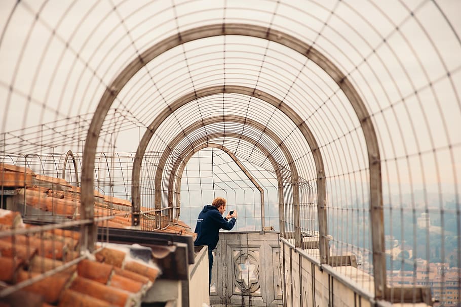 A young caucasian man taking photo with his camera on a rooftop walkway HD wallpaper