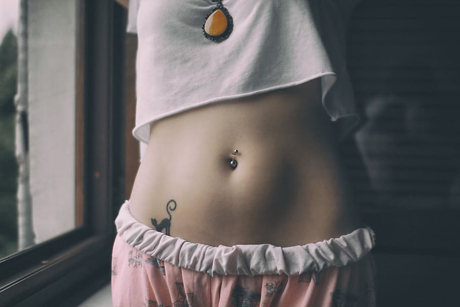 woman in white crop shirt with tattoo on her belly, midsection