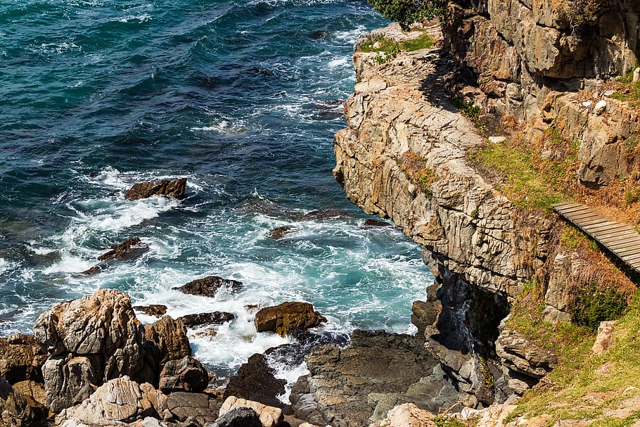 water waves hitting rocks under hill at daytime, cliff, outdoors HD wallpaper