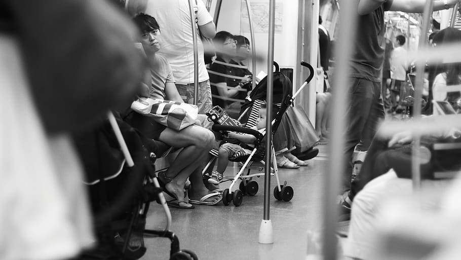 grayscale photography of baby on stroller in train, group of people